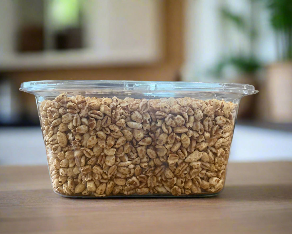 Clear plastic container filled with puffed einkorn cereal on a wooden table